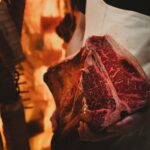 Accueil Boucher en tablier présentant une côte de bœuf maturée dans une chambre de maturation