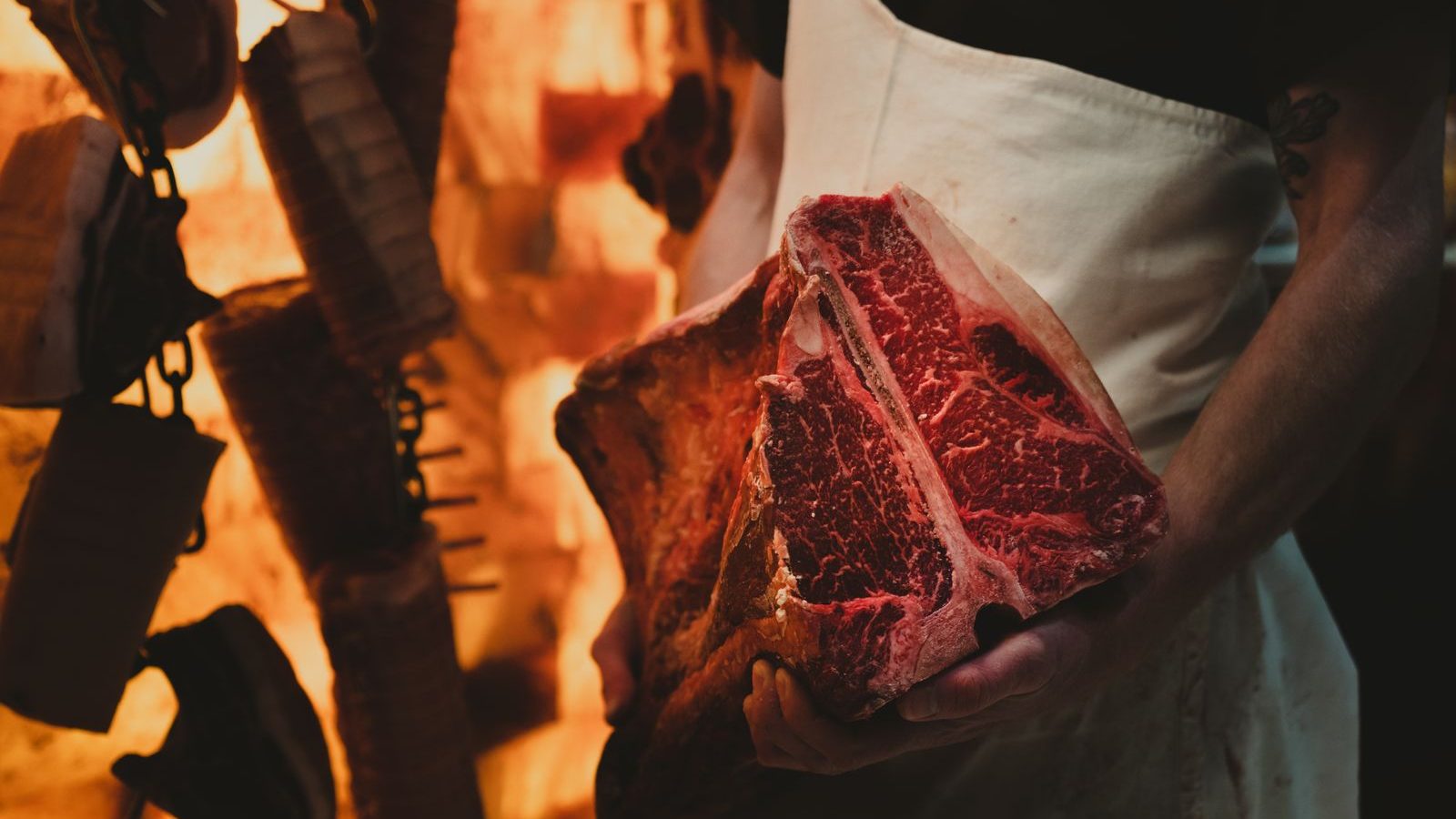 Boucher en tablier présentant une côte de bœuf maturée