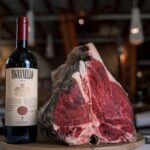 Quel vin avec quelle viande : le guide des accords qui fonctionnent Côte de bœuf crue présentée à côté d'une bouteille de vin rouge