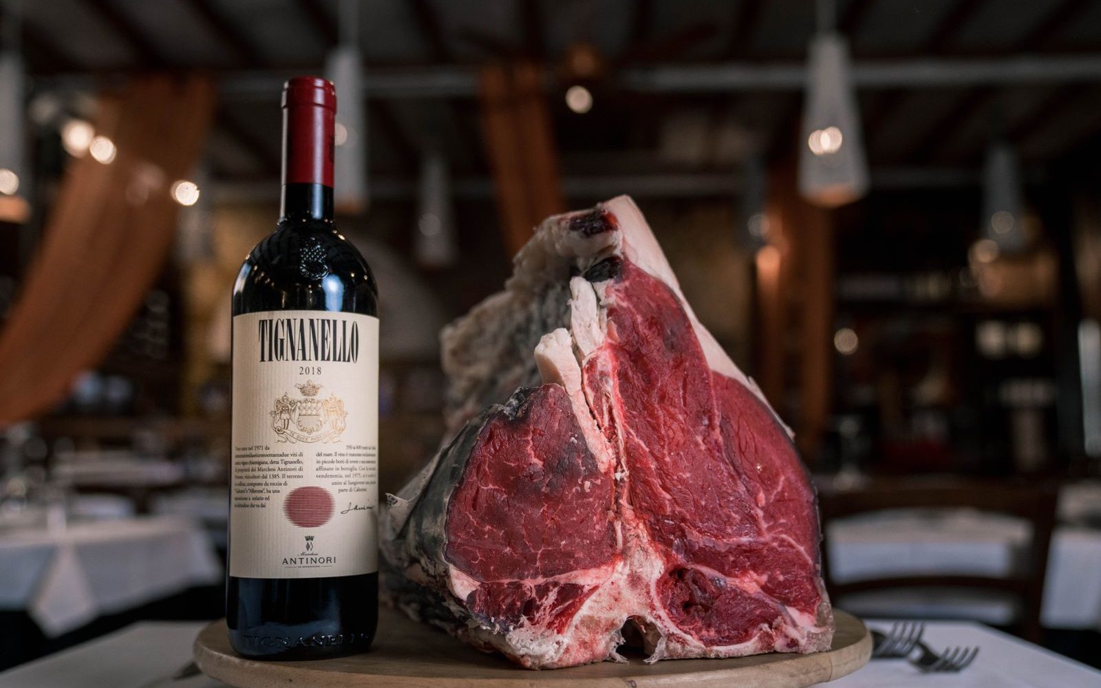 Côte de bœuf crue présentée à côté d'une bouteille de vin rouge