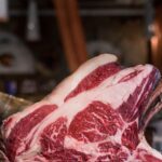 Côte de bœuf, entrecôte, faux-filet : quelles différences ? Côte de bœuf crue persillée posée sur une planche en bois