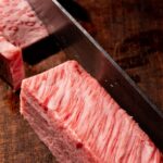 Maturation de la viande : ce que le dry aged change vraiment Tranche de bœuf wagyu très persillée découpée sur une planche