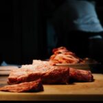 Bavette, onglet, hampe : les morceaux du boucher qu'il faut connaître Tranches de viande rouge posées sur une planche, ambiance sombre